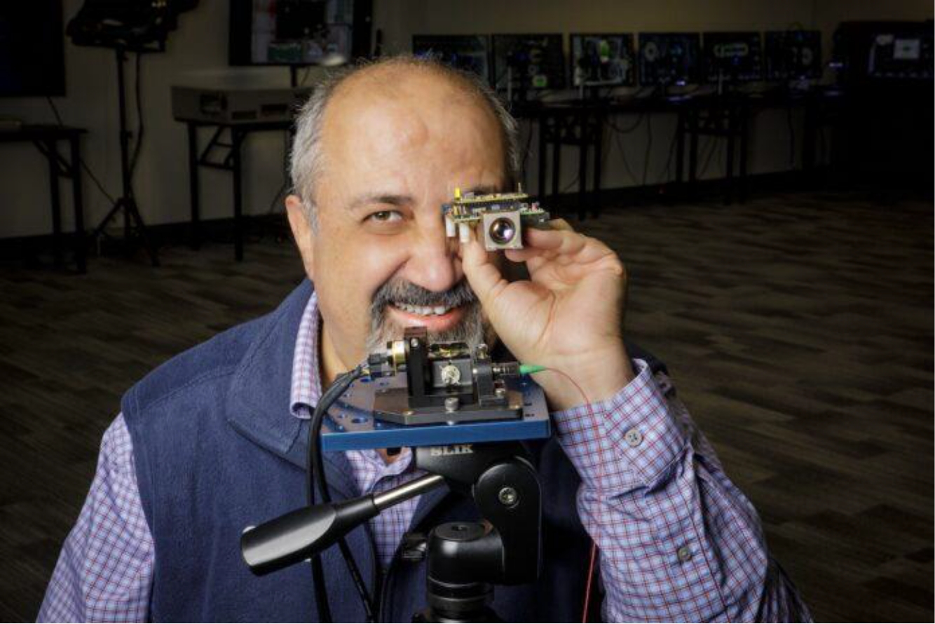man holding the SiLC Eyeonic vision system sensor in front of his eye